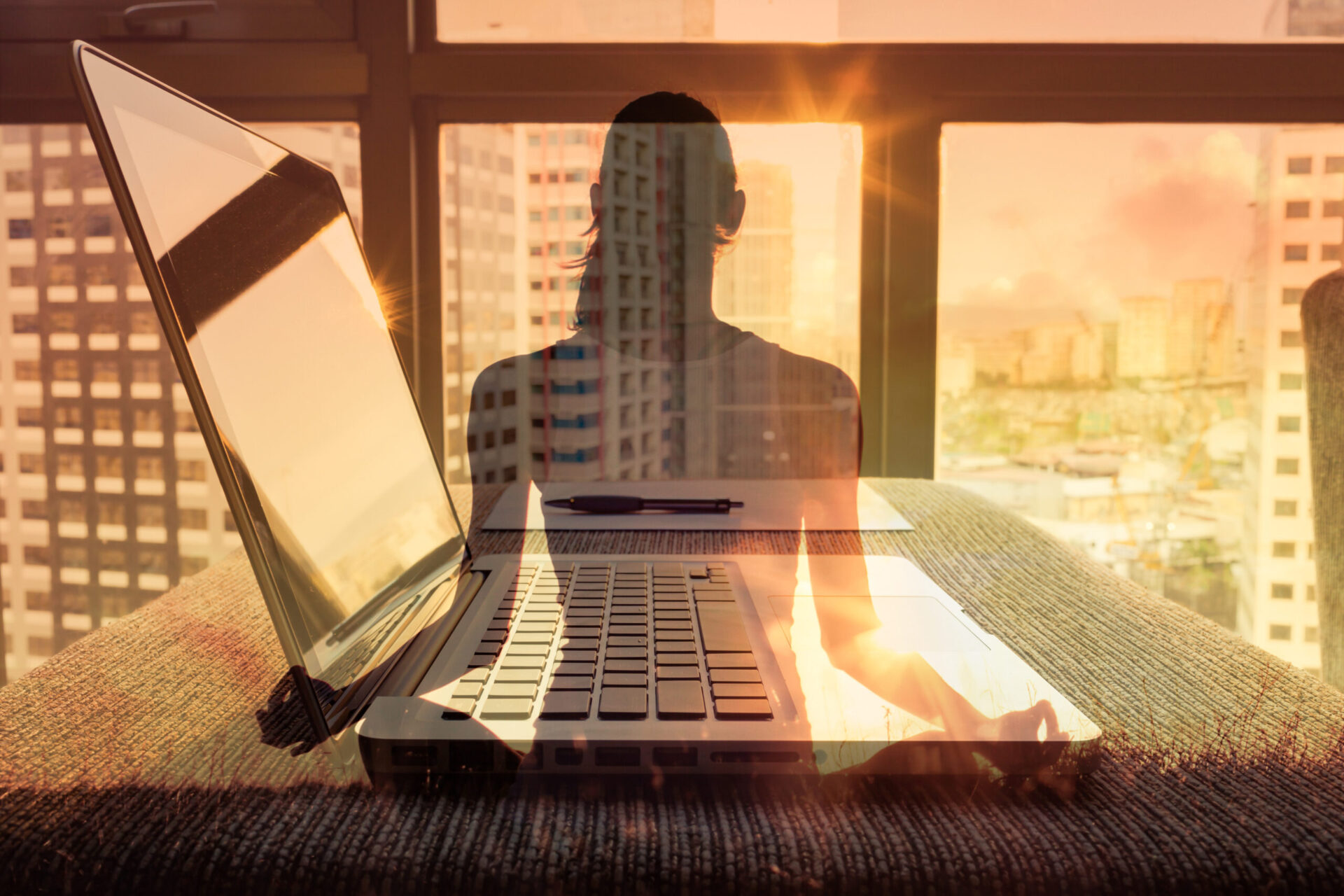 Photo of a laptop and the shadow of someone meditating in front of it