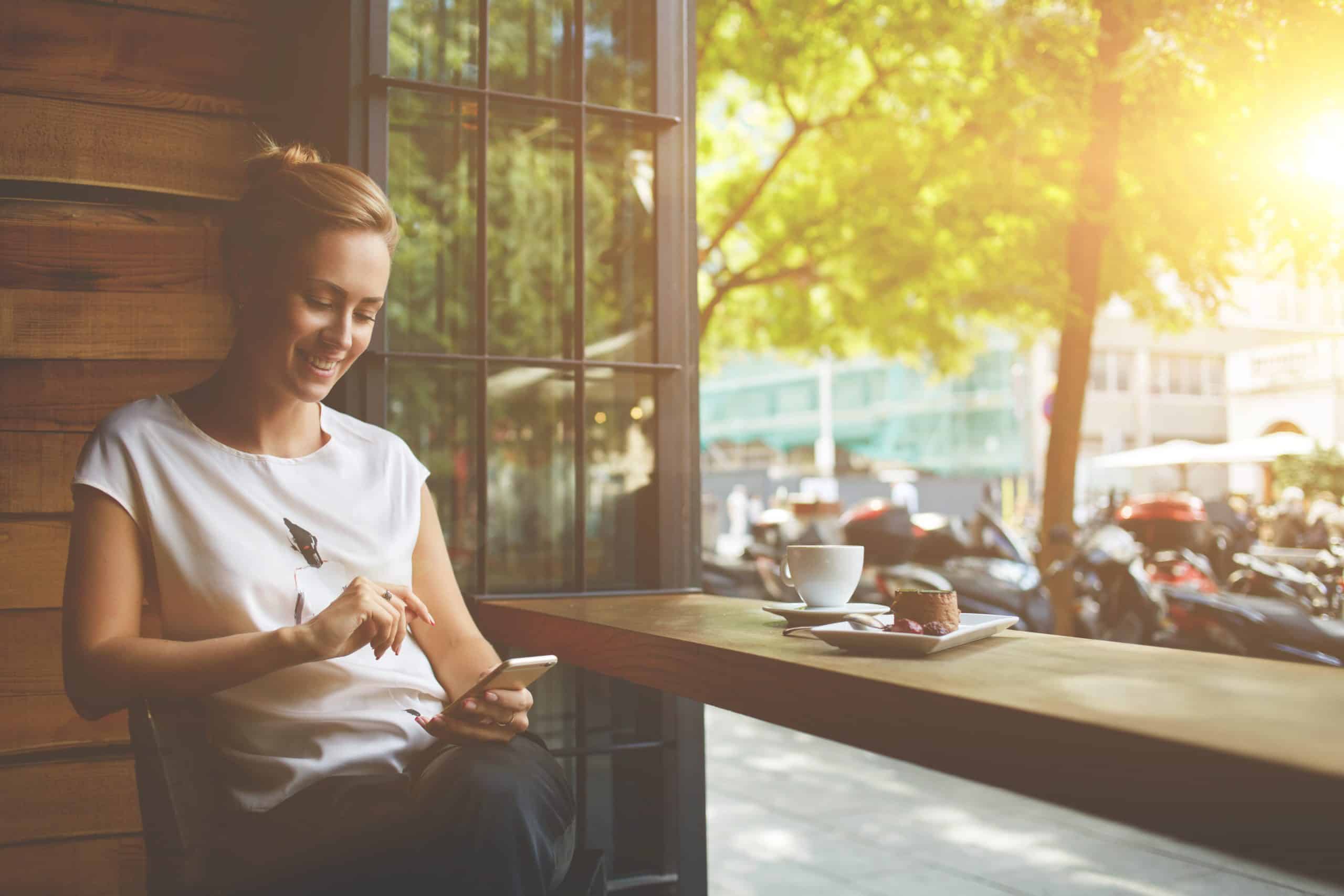 Photo of a lady sitting on her phone in a cafe