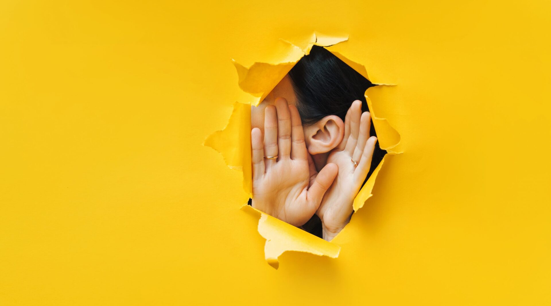 Photo of someone with their hands to their ears to mimic listening