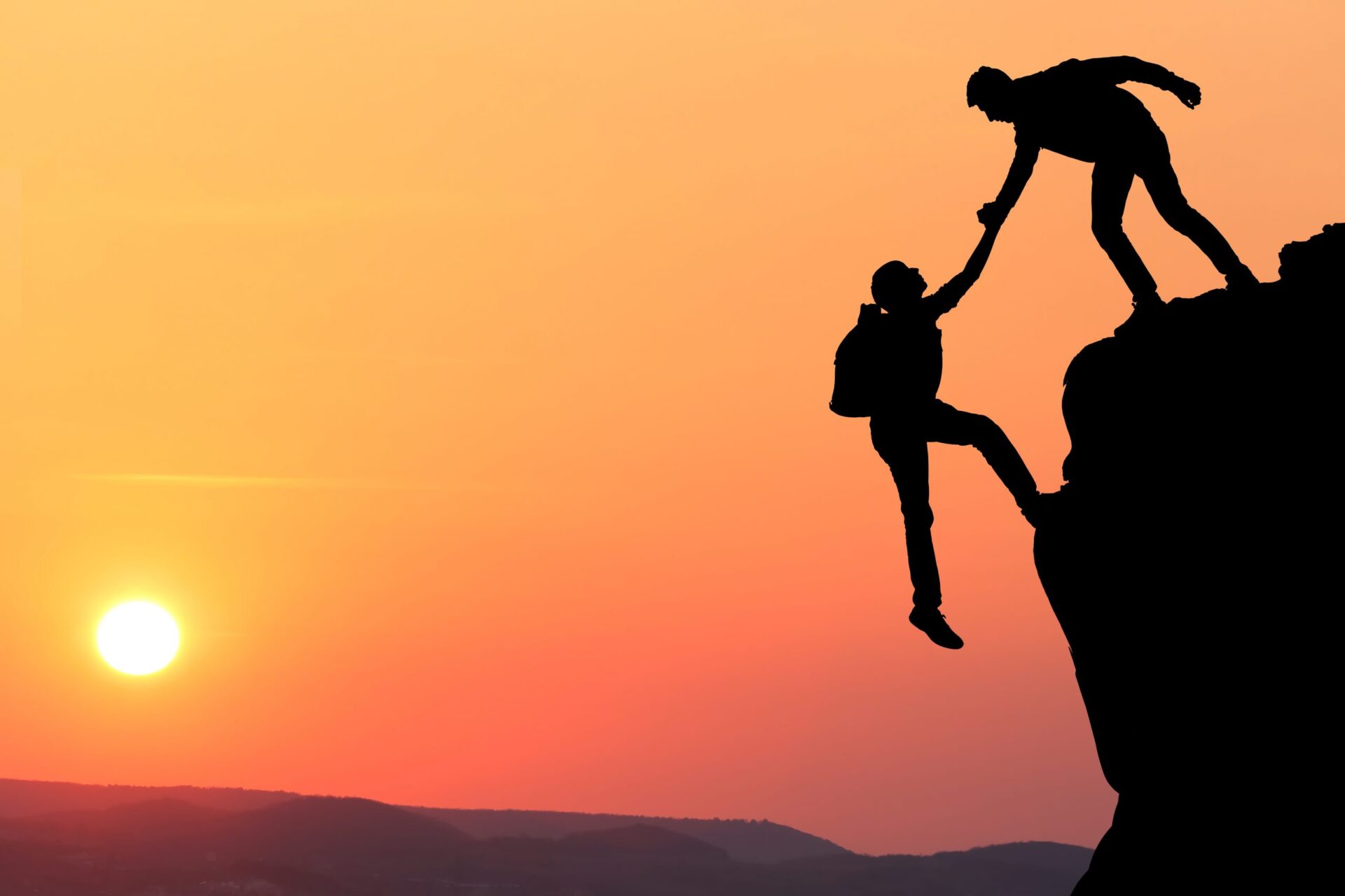 Photo of someone holding someone else over a cliff, meant to signify trust