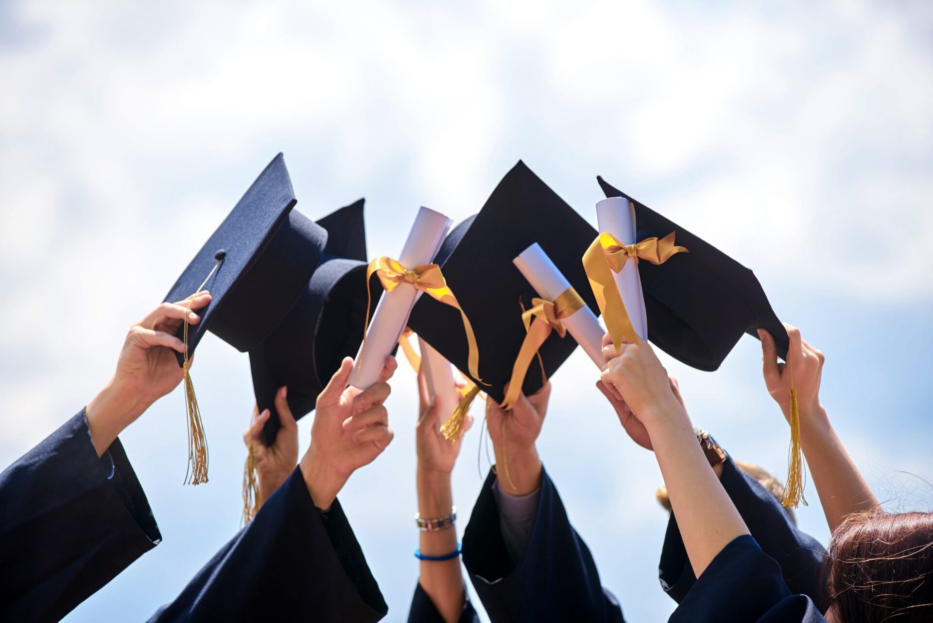 Photo of people holding up their graduation caps