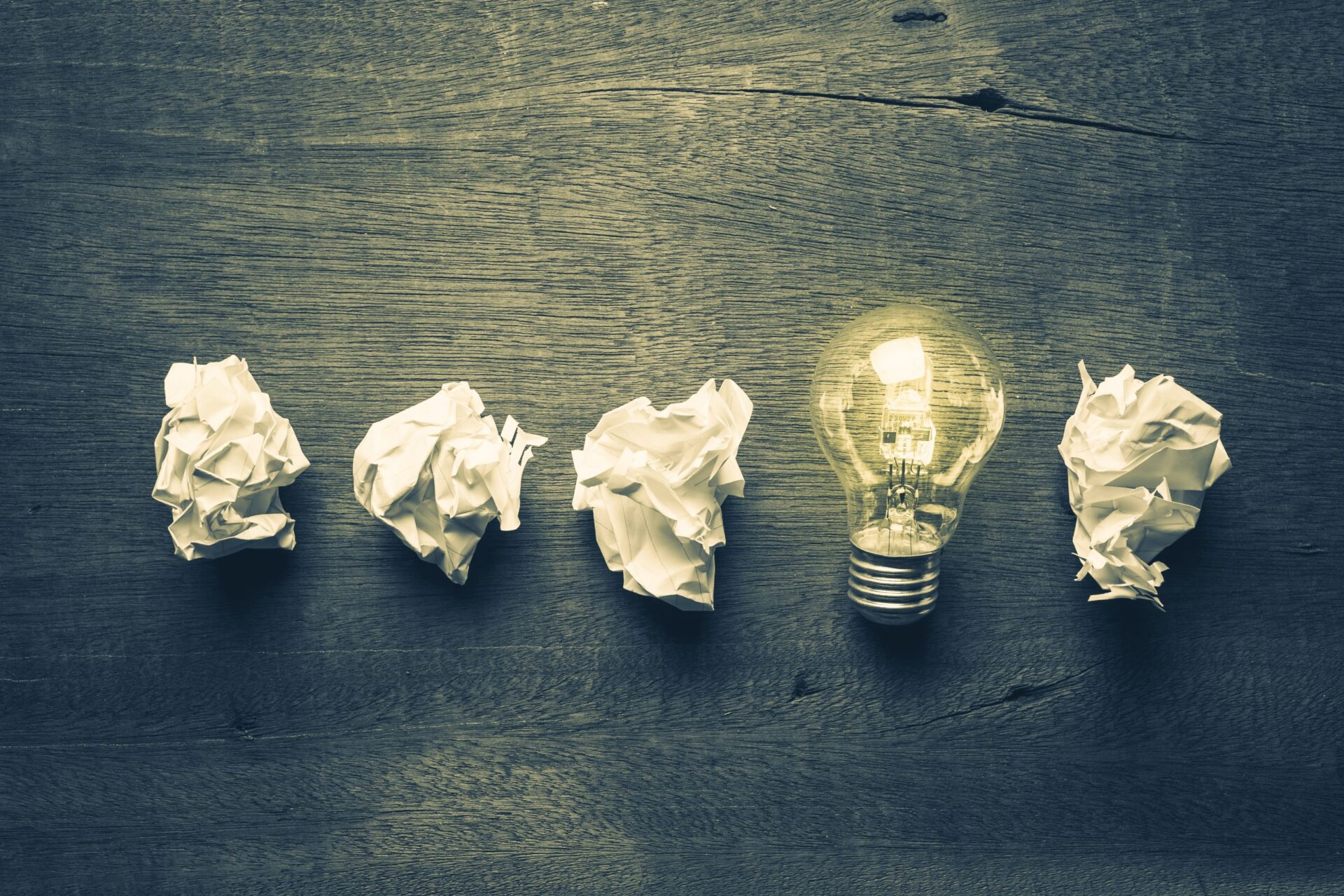 Photo of 4 scrunched up pieces of paper and a lightbulb