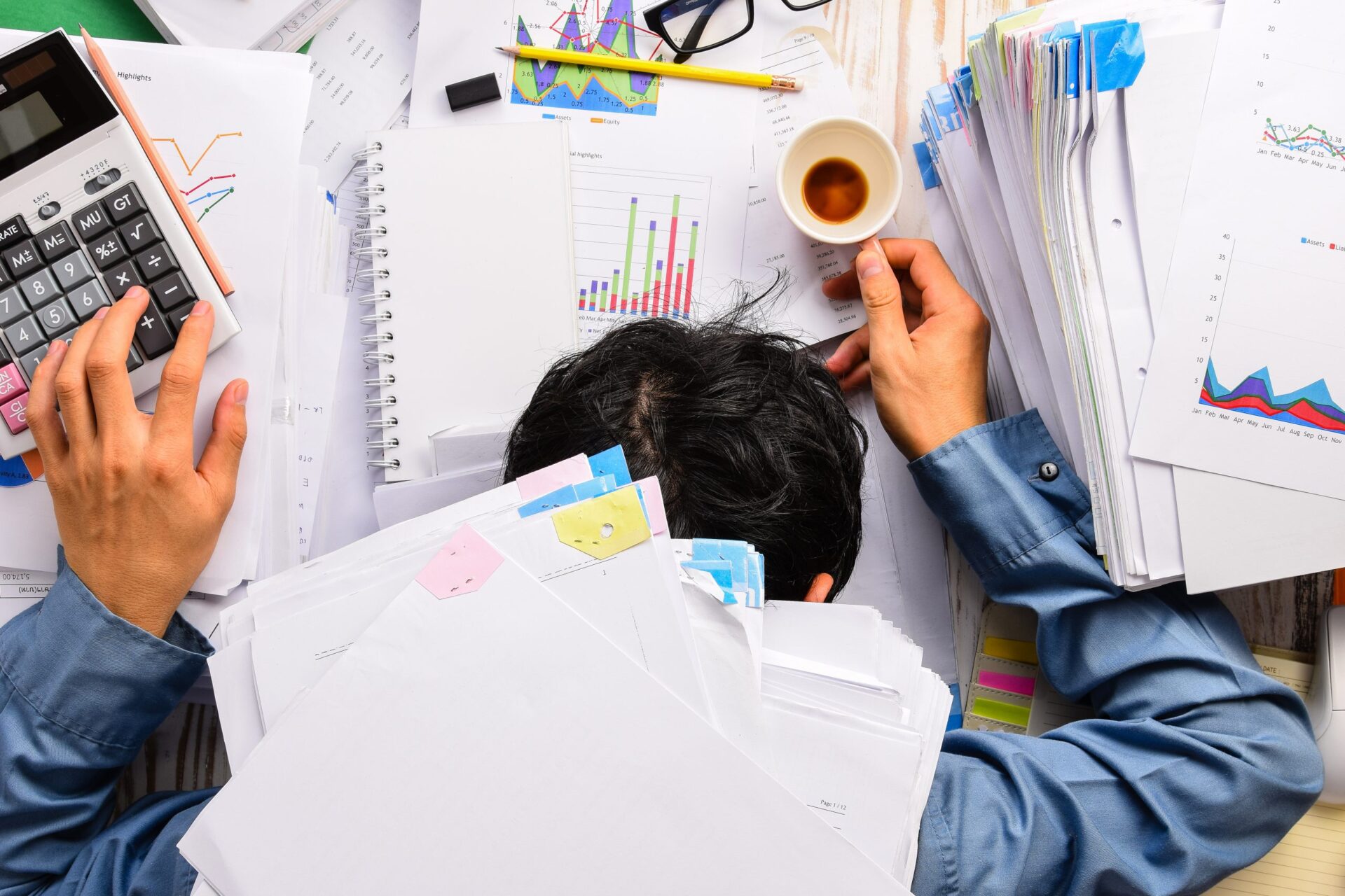 Photo of a tired man slumped over his desk at work