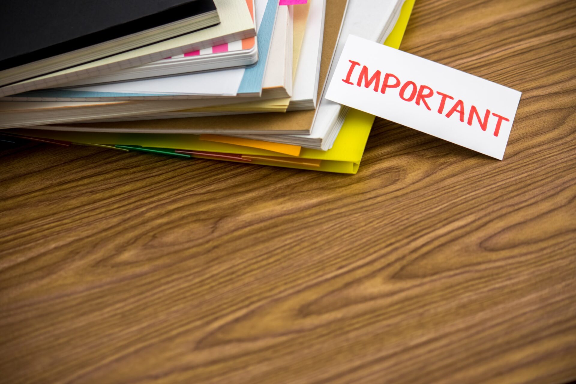 Photo of notebooks stacked up, with a piece of paper saying 'IMPORTANT' pertruding