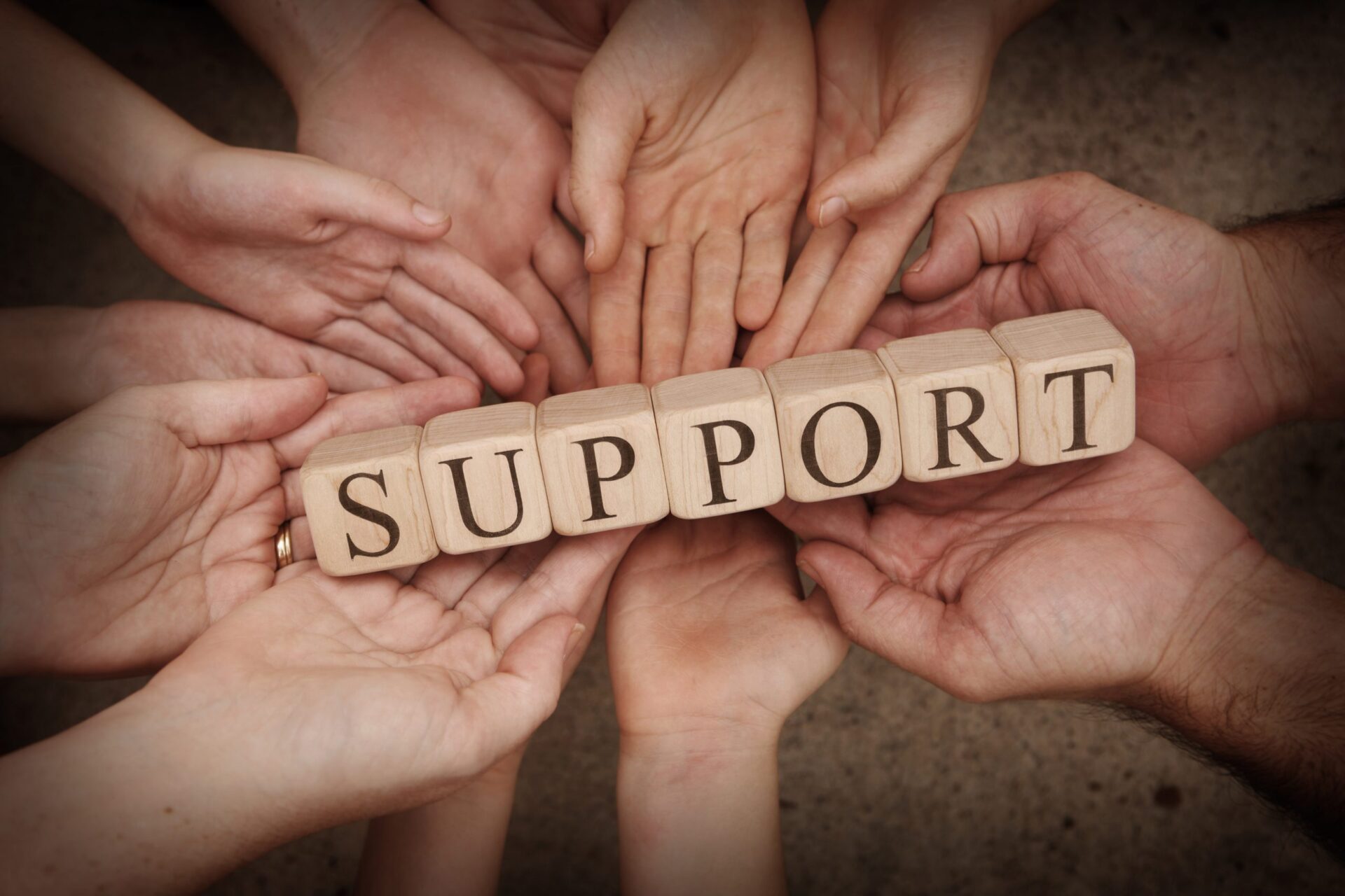 Photo of hands holding little wooden blocks that say 'SUPPORT'