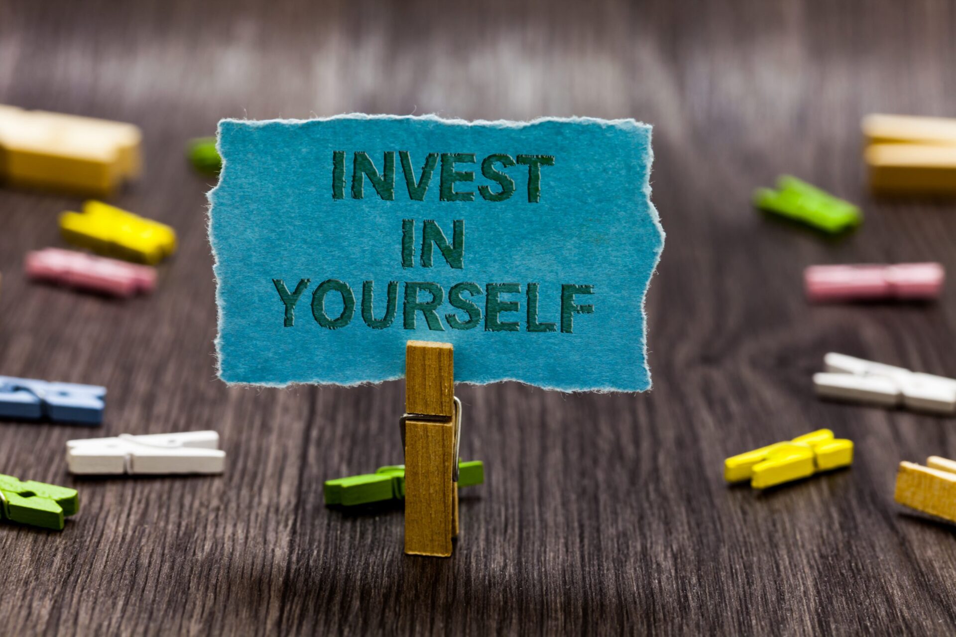Photo of a peg holding up a small sign saying 'invest in yourself'