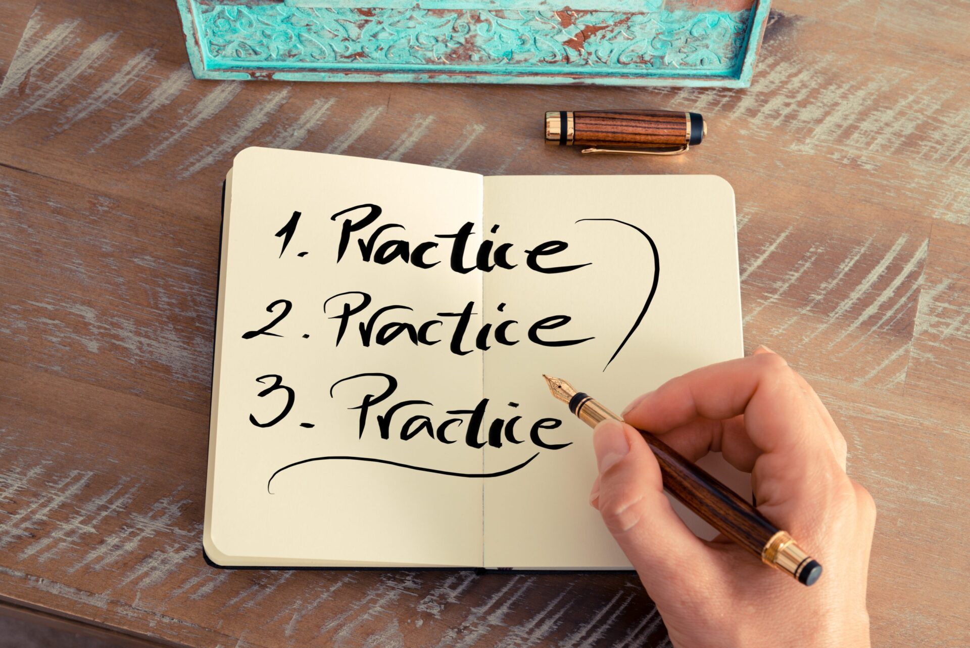 Photo of a notebook with the word 'practice' written 3 times